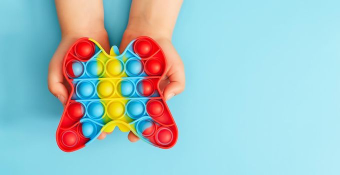 Trendy toy antistress. Anonymous child with colorful poppit game. Image of trendy Pop it fidget toy . Top view of the new sensory toy