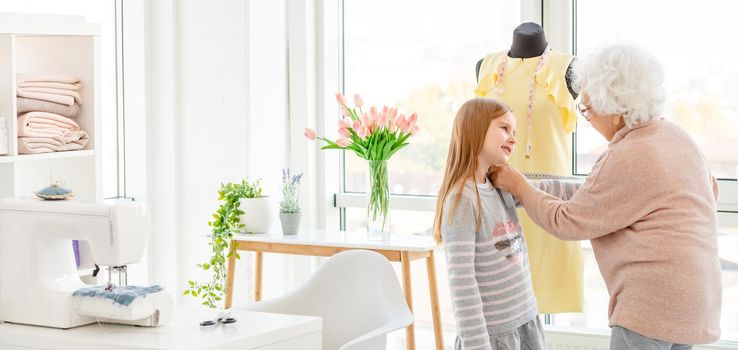 Elderly woman taking measures of granddaughter indoors