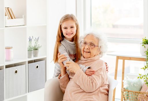 Happy little girl embracing grandmother indoors