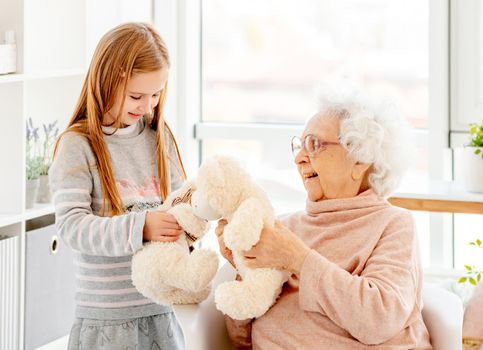 Cute little girl playing plush toys with grandmother