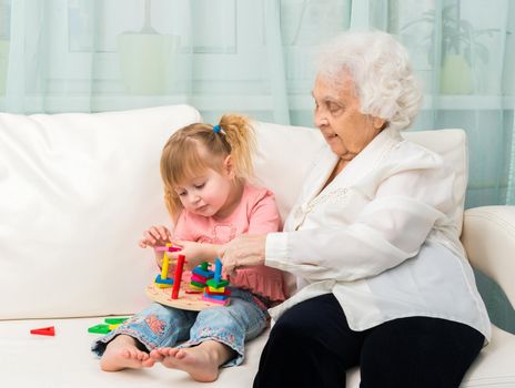 grandmother and granddaugter with cat on white sofa