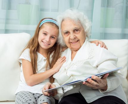 elderly woman with granddaughter with book on sofa
