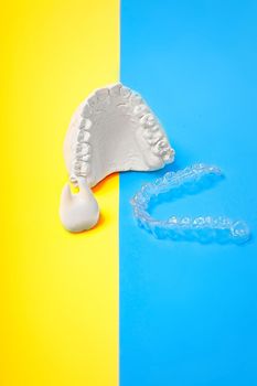 Orthodontic dental theme on blue and yellow background.Transparent invisible dental aligners or braces aplicable for an orthodontic dental treatment