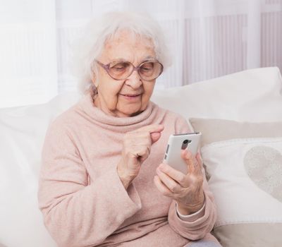 Smiling great-grandmother talking by smartphone