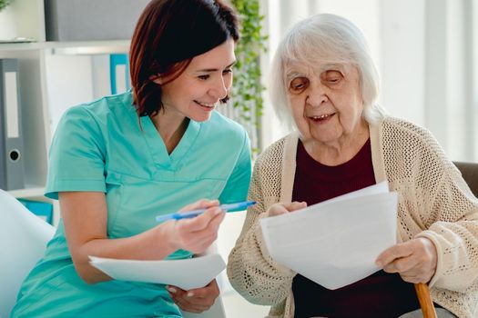 Nurse talking with elderly woman patient during visit in nursing home