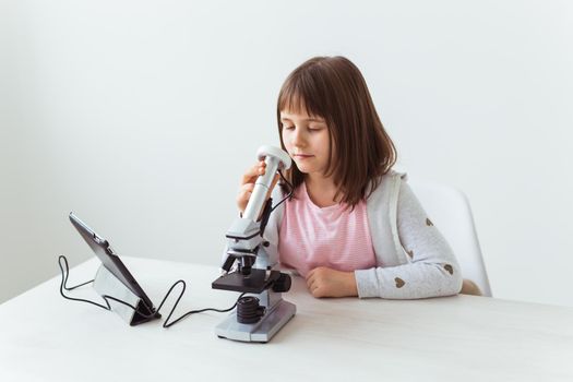 Schoolgirl using microscope in science class. Technologies, lessons and children.