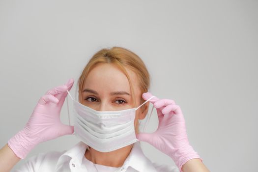 The doctor puts on a mask. Close-up portrait of medical staff. A woman in a protective mask .Isolated on a white background. Healthcare, cosmetology and medical concept.