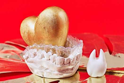 Heart of gold on a red background in invisible dental aligners or braces aplicable for an orthodontic dental treatment