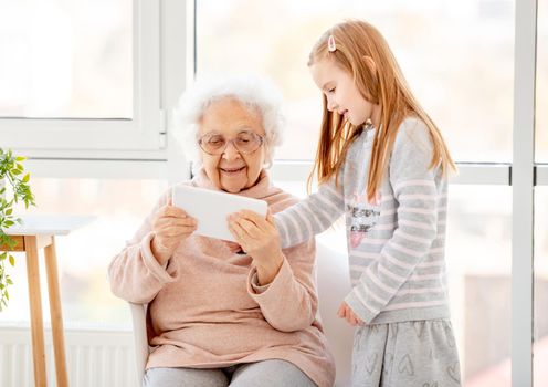 Cute little girl teaching great-grandmother to use new technologies