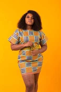 Young beautiful african american girl with an afro hairstyle. Portrait on yellow background.