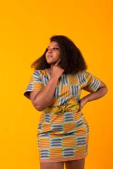 Young beautiful african american girl with an afro hairstyle. Portrait on yellow background.
