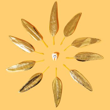 Creative concept of smiling sun shaped tooth on yellow background, flat lay