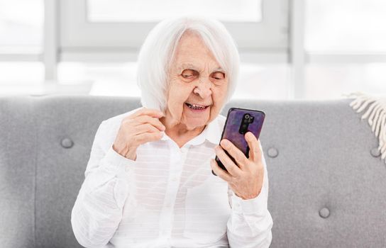 Modern ederly woman talking with friends by video using smartphone. Concept of old generation and new technologies