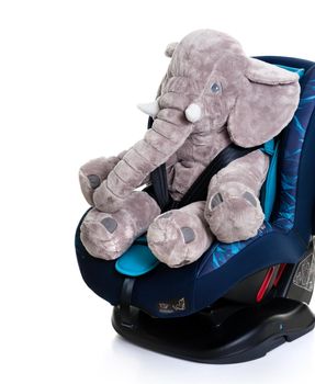 cute elephant doll in blue child safety seat over white background, seat designed specifically to protect children from injury or death during collisions.