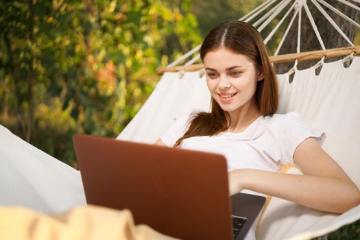 woman with laptop lies in hammock freelance travel. High quality photo