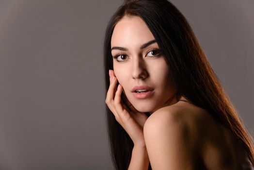 Happy beautiful woman smiling and holding his hand near the face. Woman on a black background