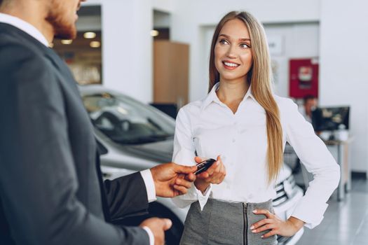 Young attractive woman buying a new car in car salon close up