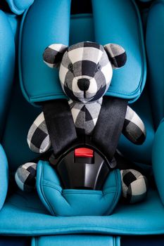 teddy bear in blue child safety seat, seat designed specifically to protect children from injury or death during collisions.
