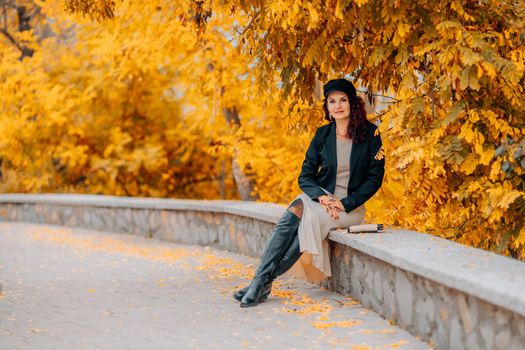 A young, beautiful girl sits on a background of yellow autumn foliage. Autumn Park