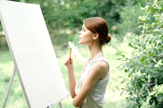 Cheerful woman artist nature easel creative art. High quality photo