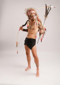 the man in the image of indigenous peoples of America with a bow and arrow poses on a white background