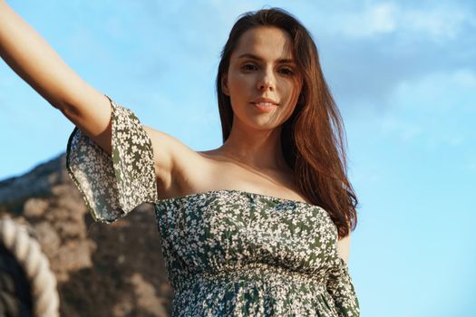 Young pretty woman in floral dress posing on yacht in the sea