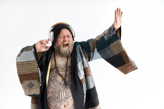 Fat stylish bearded tattoed caucasian man with big belly is posing and dancing wearing ethnic kimono