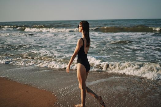 woman in black swimsuit walking on the beach ocean summer. High quality photo