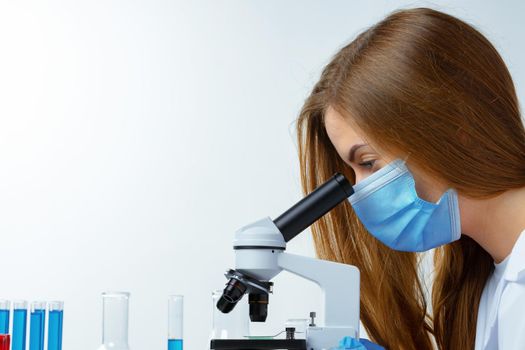 Woman scientist looking through a microscope in laboratory. Scientific research