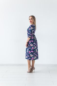 Fashionable young woman in beautiful dress posing at studio. Isolated over white.