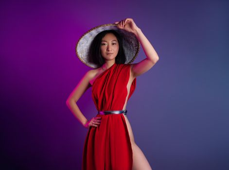 the asian woman in red cape and asian hat posing on bright neon background