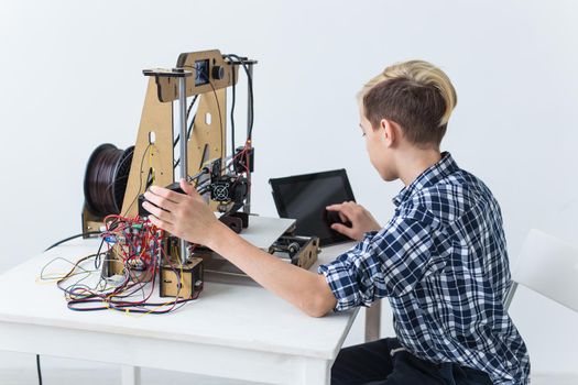 Education, children, technology concept - teen boy is printing on 3d printer