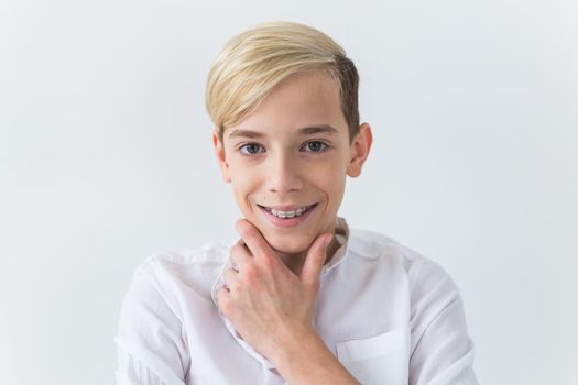 Closeup of teen boy with braces on teeth smiling on white background. Dentistry and teenager concept.