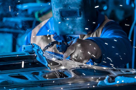 The process of welding spark welding during the repair of an automobile door in the working shop of an industrial plant.