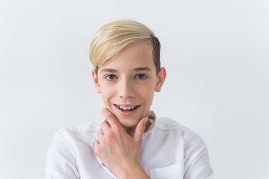 Closeup of teen boy with braces on teeth smiling on white background. Dentistry and teenager concept.