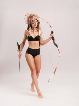 the woman in the image of indigenous peoples of America with a bow and arrow poses on a white background