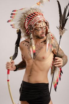the man in the image of indigenous peoples of America with a bow and arrow poses on a white background