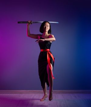 the slender Asian woman in a black dress with a katana in her hand image of a samurai on a neon background