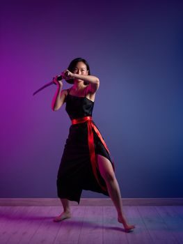 the slender Asian woman in a black dress with a katana in her hand image of a samurai on a neon background