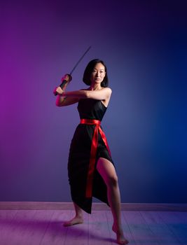 the slender Asian woman in a black dress with a katana in her hand image of a samurai on a neon background