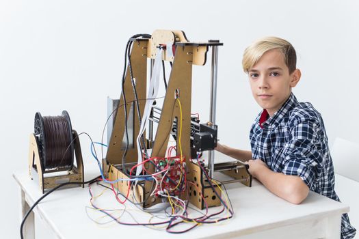 Education, children, technology concept - teen boy is printing on 3d printer