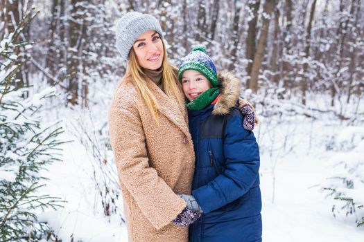 Portrait of happy mother with child son in winter outdoors. Single parent.