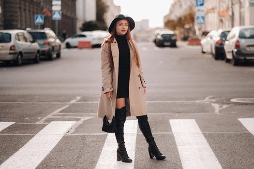 Stylish young woman in a beige coat in a black hat on a city street. Women's street fashion. Autumn clothing.Urban style.