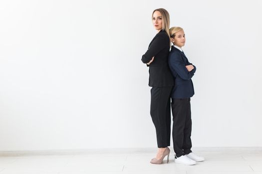 Teenager and single parent - Young mother and son standing together, back to back on white background with copyspace.