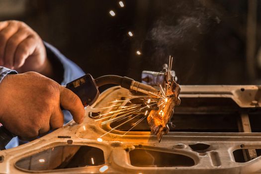 A close-up of the process of repairing a car door using welding. Welding and metal works at the factory.