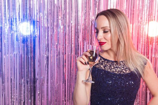 drinks, holidays and celebration concept - smiling woman in evening dress with glass of sparkling wine over shiny background