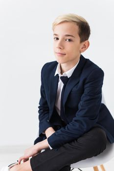 Portrait of stylish school boy teenager in white shirt and jacket against white background with copy space