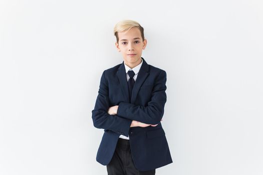 Portrait of stylish school boy teenager in white shirt and jacket against white background with copy space