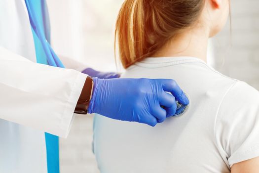 Doctor hands with stethoscope listening to heartbeat of woman patient close up