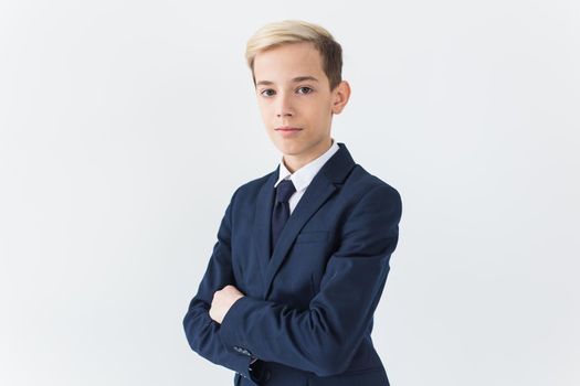 Portrait of stylish school boy teenager in white shirt and jacket against white background with copy space